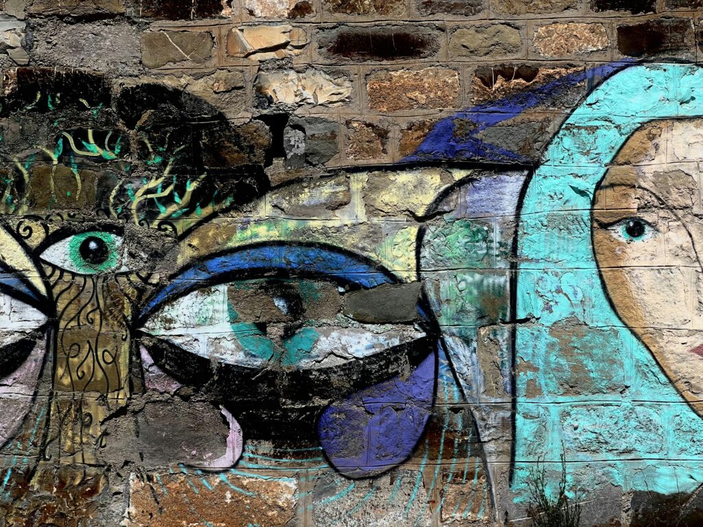 Graffiti art featuring abstract faces and eyes on brick wall